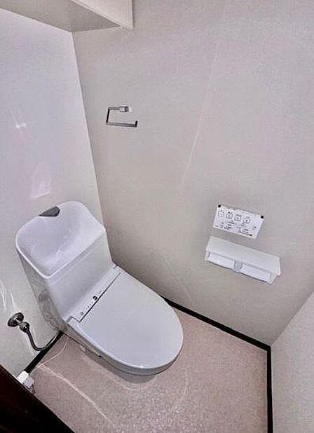 全体を明るいトーンで統一した、清潔感あふれるトイレ空間。手洗い一体型デザインの便器を採用しており、すっきりとした印象を与えます。