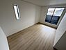 寝室：明るい陽射しが差し込む寝室です。ナチュラルなフローリングが落ち着いた雰囲気を演出します。大きな窓があり開放感のある空間です。シンプルな内装でお好きなインテリアを楽しめます。