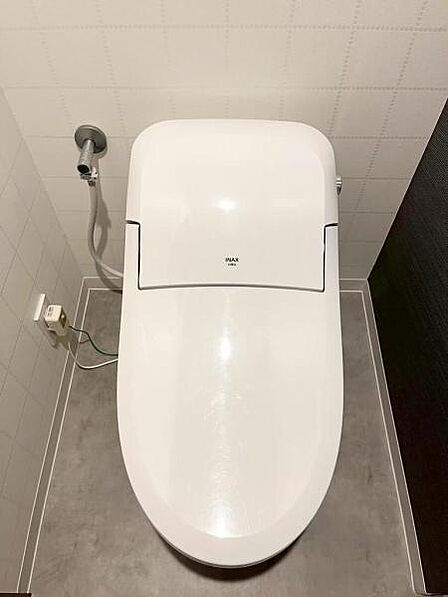 シンプルなデザインで清潔感を感じられるトイレです。床や壁も落ち着いた色合いでまとまっています。
