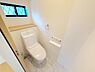 トイレ：明るい空間に設計され窓から自然光が差し込むトイレです。清潔感のある白を基調としたデザインになっています。収納スペースも確保されており機能的なレイアウトです。壁のリモコン操作で利便性も感じられます。
