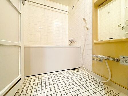 シンプルなデザインの洗面台・洗面所でタイル張りの床と壁が特徴的です。鏡やシャワー水栓が備わっており使いやすい空間です。浴槽と一体となったレイアウトで毎日の準備もスムーズに行えます。