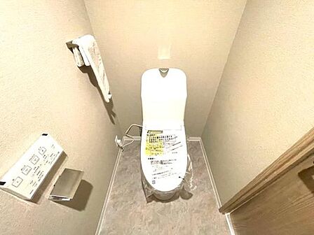明るく清潔感のあるトイレです。壁付けのペーパーホルダーやリモコンが備え付けられておりすっきりとした空間になっています。タオル掛けも使いやすい位置に設置されています。シンプルなデザインが特徴的です。