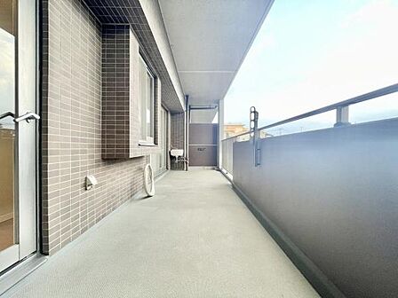 ゆとりのある広々としたバルコニーが特徴です。奥行きがあるため多様な用途にも活用できます。採光も良好で開放感があります。建物側のタイル貼りが印象的です。屋根付きで天候の影響も受けにくい設計です。
