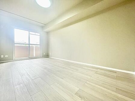 明るい光が差し込む寝室です。広々としたスペースで家具のレイアウトも自由度があります。シンプルな内装が特徴的で落ち着いた雰囲気を感じられます。バルコニーにつながる窓が部屋に開放感を与えています。