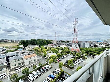 爽やかな空と開放感のある現地からの眺望です。遠くまで見渡せる景色が印象的です。周囲には緑も点在しており圧迫感を感じにくい立地が魅力です。住宅街や駐車場が広がる落ち着いた環境です。