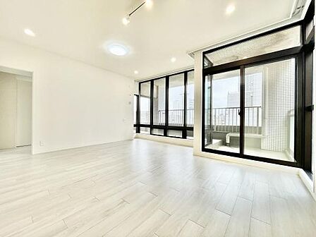 大きな窓からたっぷりと自然光が差し込む明るいリビングです。フローリングの床が空間を広く感じさせすっきりとした印象です。開放感のあるガラス扉がバルコニーへと繋がっています。