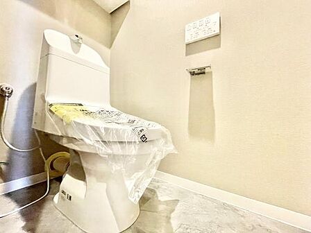 清潔感のあるトイレ空間です。壁付けのリモコン操作が可能なタイプで快適にご利用いただけます。床や壁も明るい色調ですっきりとした印象です。新生活におすすめの設備が整っています。