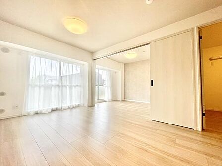 大きな窓からたっぷりと自然光が入るリビングです。明るく開放感のある空間が広がります。スライド式の扉で空間の使い分けが可能です。すっきりとした内装が特徴です。柔らかなフローリングの色合いが魅力です。
