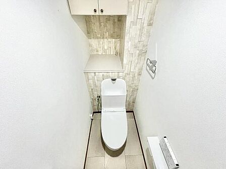 トイレはホワイトを基調とした清潔感のある空間です。壁面のデザインクロスがすっきりとした印象を演出しています。収納スペースもしっかり備わっており使いやすさにも配慮されています。