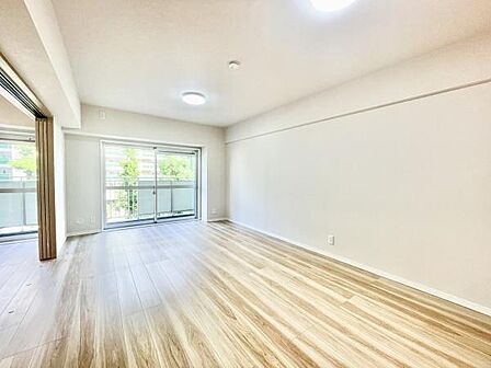 リビングには大きな窓があり室内が明るく感じられます。ナチュラルな色合いの床材が空間を広く演出しています。天井までしっかりとした高さが確保されておりすっきりとした印象です。