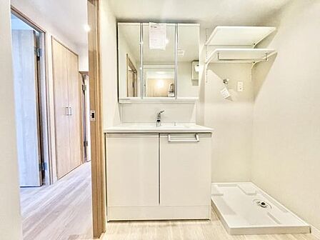 白を基調とした洗面台・洗面所で清潔感のある空間が広がっています。収納スペースも充実しており使いやすさに配慮された設計です。大型のミラーが設置されており毎日の身支度をスムーズに行えます。