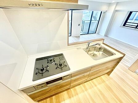 明るい床材とシンプルなデザインが調和したキッチンです。三口コンロを備えており調理の幅が広がります。収納スペースも充実しており整理整頓がしやすい仕様です。