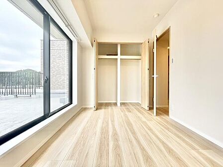 大きな窓から光が差し込む洋室です。床の色合いが明るく全体的に開放感があります。クローゼット収納も備わっており使い勝手の良い空間です。シンプルな内装で様々な家具とも調和しやすいです。