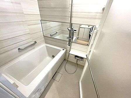 上品な大理石調パネルとワイドミラーがラグジュアリーな雰囲気を演出するバスルーム。手すり付きの安全設計と清潔感溢れるゆったりとした浴槽で、一日の疲れを癒やす心地よいひとときを過ごせます。
