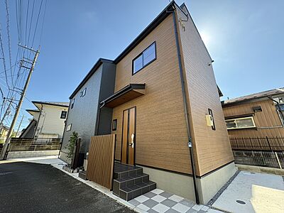 外観：落ち着いたブラウンとシックなグレーのツートンカラーが美しい外観。新築の輝きが、ご家族の新しい生活を明るく照らします。広々としたアプローチで、お子様との外出もスムーズです。