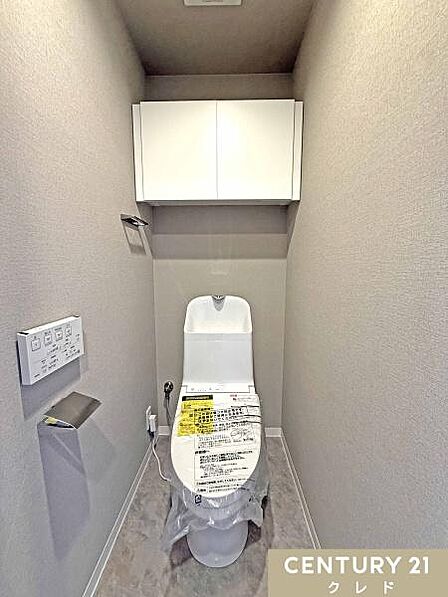 ウォシュレット一体型トイレに新規交換。天井近くまで届く吊り戸棚が新設されているため、トイレットペーパーのストックや掃除用品をすっきりと収納。