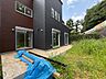 外観：隣接する住宅と緑地が見える物件の外観