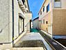 外観：建物に挟まれた細い通路と住宅外観