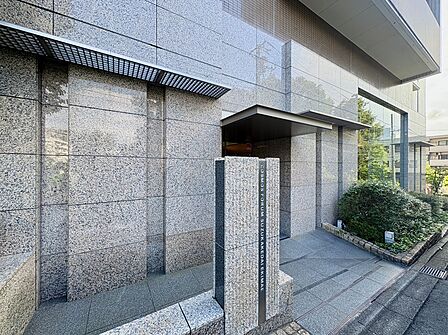 タイル張りのマンション外観とエントランス前の歩道