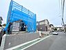 外観：青い養生シートで覆われた建築中の建物と前面道路