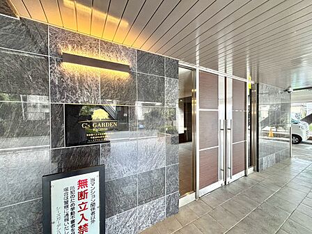 石張りの壁と照明があるマンションのエントランス