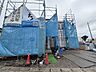 外観：青い養生シートで覆われた建築中の建物