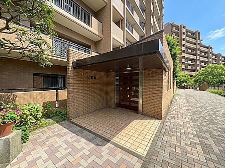 マンションの敷地入口と建物外観の一部が見える写真です
