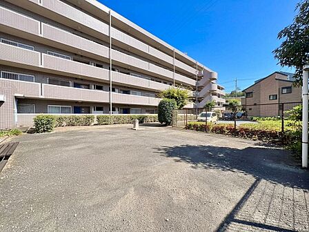 広々とした建物前の駐車スペースと周辺の住宅街