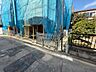 外観：建築中の建物と前面道路、植栽が見える外観