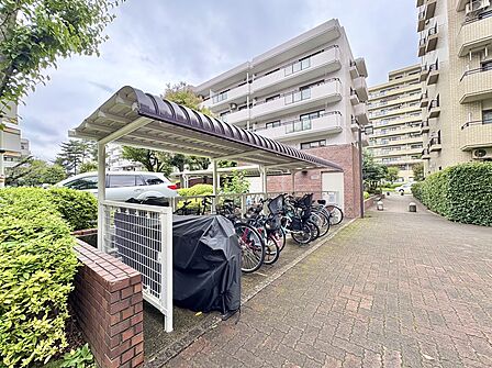 屋根付きの駐輪場と植栽のある敷地内通路