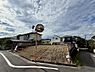 外観：前面道路と傾斜地に建つ住宅の外観