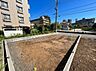外観：建築中の区画された土地周囲に住宅や建物が見える