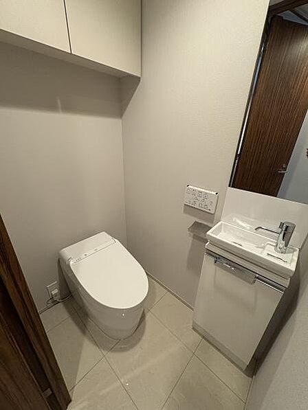 ゆとりある広さのトイレルーム。スタイリッシュなタンクレストイレで温水洗浄便座付！丸い大きな鏡がおしゃれです。
