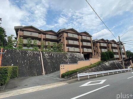 高台に佇む、落ち着いた雰囲気のマンション。周囲の緑と調和する重厚感のある外観が、穏やかな住環境を感じさせます。