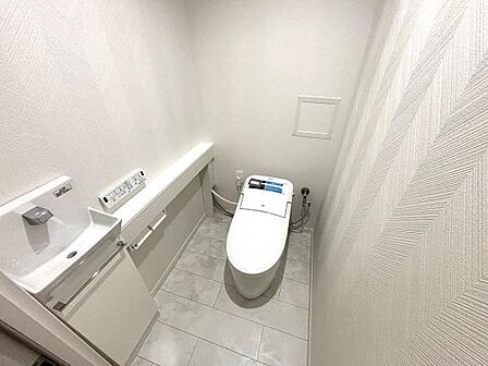 白を基調としたトイレ空間です。セパレートタイプの手洗い器はセンサー式で機能性もあります。リビング続きのタイル調フローリング床を採用。