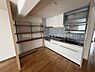 キッチン：白を基調としたキッチンで清潔感があります。壁面には便利なオープン棚が設置されています。タイル張りの壁がアクセントになっています。ワークスペースも広々と取られています。収納スペースが豊富です。