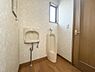トイレ：窓があり通気性に配慮されたトイレです。床材と壁紙の組み合わせが落ち着いた印象を与えます。手洗い器と小便器が設置されています。ドアの開閉もスムーズです。照明の明るさも十分です。