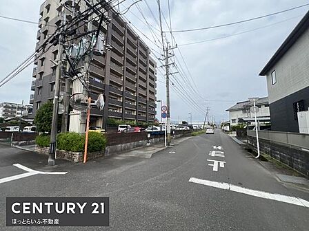 建物や道路が整然とした雰囲気の外観写真です。周囲に高い建物があり住環境の様子がうかがえます。電線もすっきりと整備されており地域の街並みが特徴的です。建物前の歩道も広めで移動も便利です。