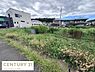 外観：閑静な住宅街に位置する現地土地写真です。周辺には戸建て住宅が建ち並び落ち着いた雰囲気が広がっています。敷地は道路に面しておりアクセスも便利です。空が広く見える開放的なロケーションが特長です。