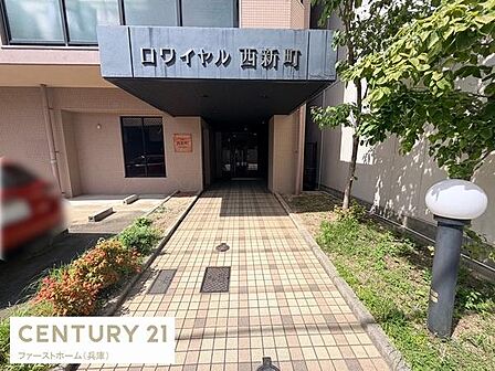 建物のエントランスは広々としたアプローチが印象的です。タイル張りの通路が清潔感を感じさせます。植栽や外灯も整えられており管理の良さが窺えます。日差しもたっぷり差し込む明るい雰囲気です。