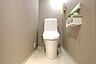トイレ：シンプルで洗練されたデザインのトイレ空間です。収納棚が設置されており小物やペーパーもすっきりと整理できます。壁や床のトーンも落ち着いていて清潔感があります。