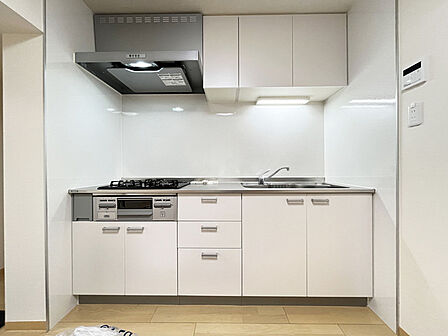 壁付のキッチンは上部に収納が作りやすいのがメリット。空間を有効活用したすっきりとしたデザイン。
